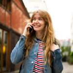 smiling young woman talking with mobile phone outside in city